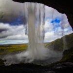 From the front, the view is already breathtaking — the water plunging dramatically from a tall cliff with mist swirling in the air. But once you take the narrow, wet trail that curves behind the falls, it becomes a whole different experience.