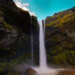 Kvernufoss, dropping nearly 100 feet over a lava rock cliff into a peaceful green canyon.