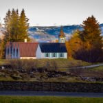 Þingvellir Church-its white walls and dark roof standing out against the green fields and surrounding lava formations.