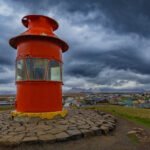 Perched on a small island just beyond the harbor, this bright red lighthouse immediately will catch your attention with its pop of color against the cool tones of the sea and sky.