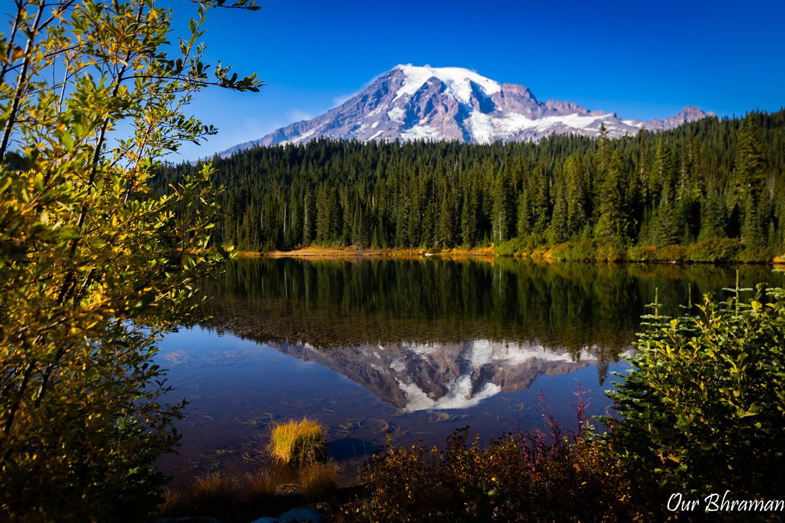 The snow-capped peak of Mount Rainier is perfectly reflected in the calm waters of Reflection Lake