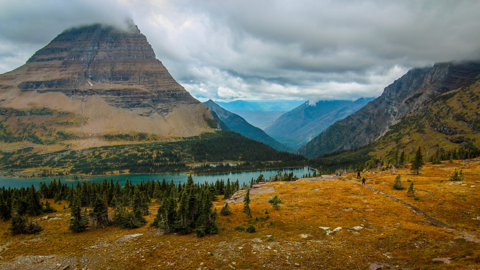 The massive, triangular peak of Bearhat Mountain towers over the turquoise waters of Hidden Lake at Glacier National Park, Montana.