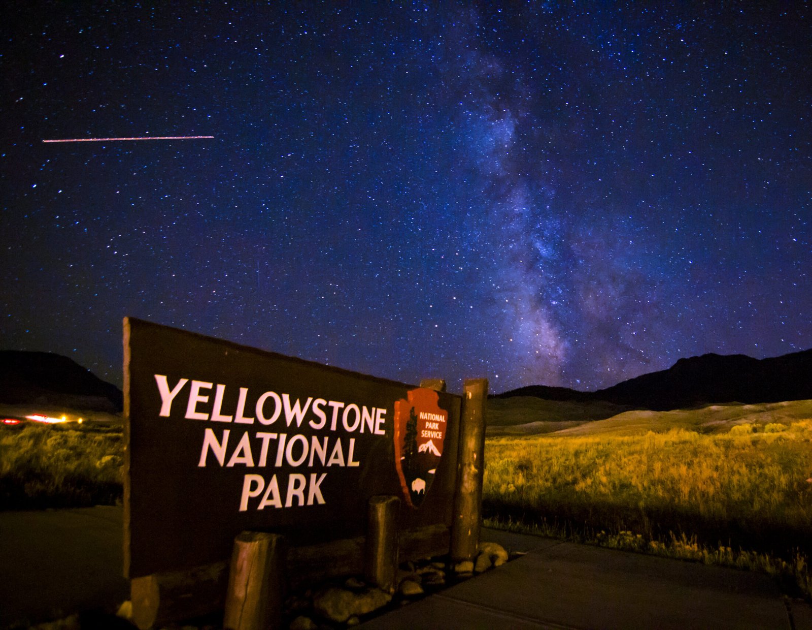 A vibrant night sky filled with the Milky Way galaxy and a passing shooting star in Yellowstone