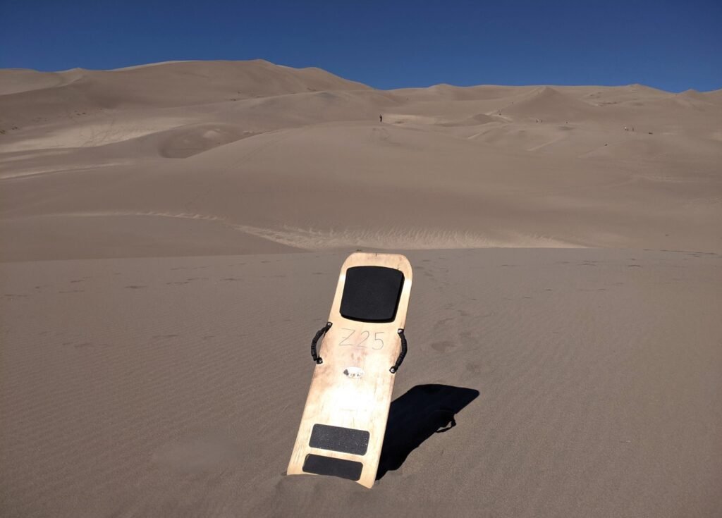 Our Sandboard standing among the vast, rolling desert dunes at Great Sand Dunes National Park