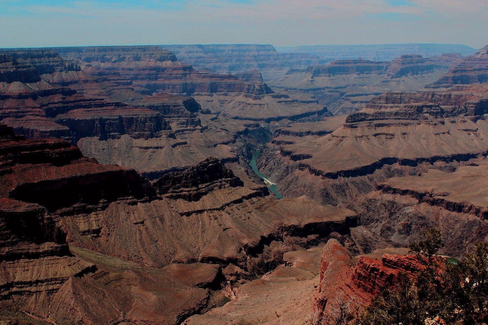 Looking down into the deep, expansive gorges of the Grand Canyon in Arizona, with the green Colorado River winding through the canyon floor